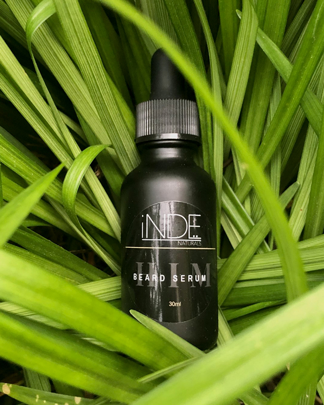 Inde Naturals beard serum bottle placed in green foliage highlighting natural branding