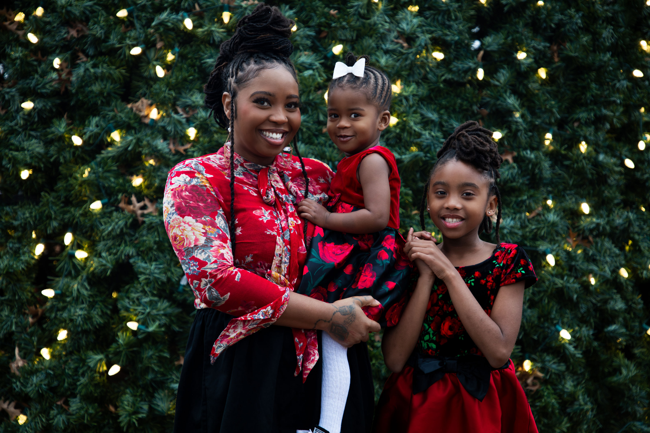 Mother and daughters posing together in coordinated red and black outfits during Christmas portrait session