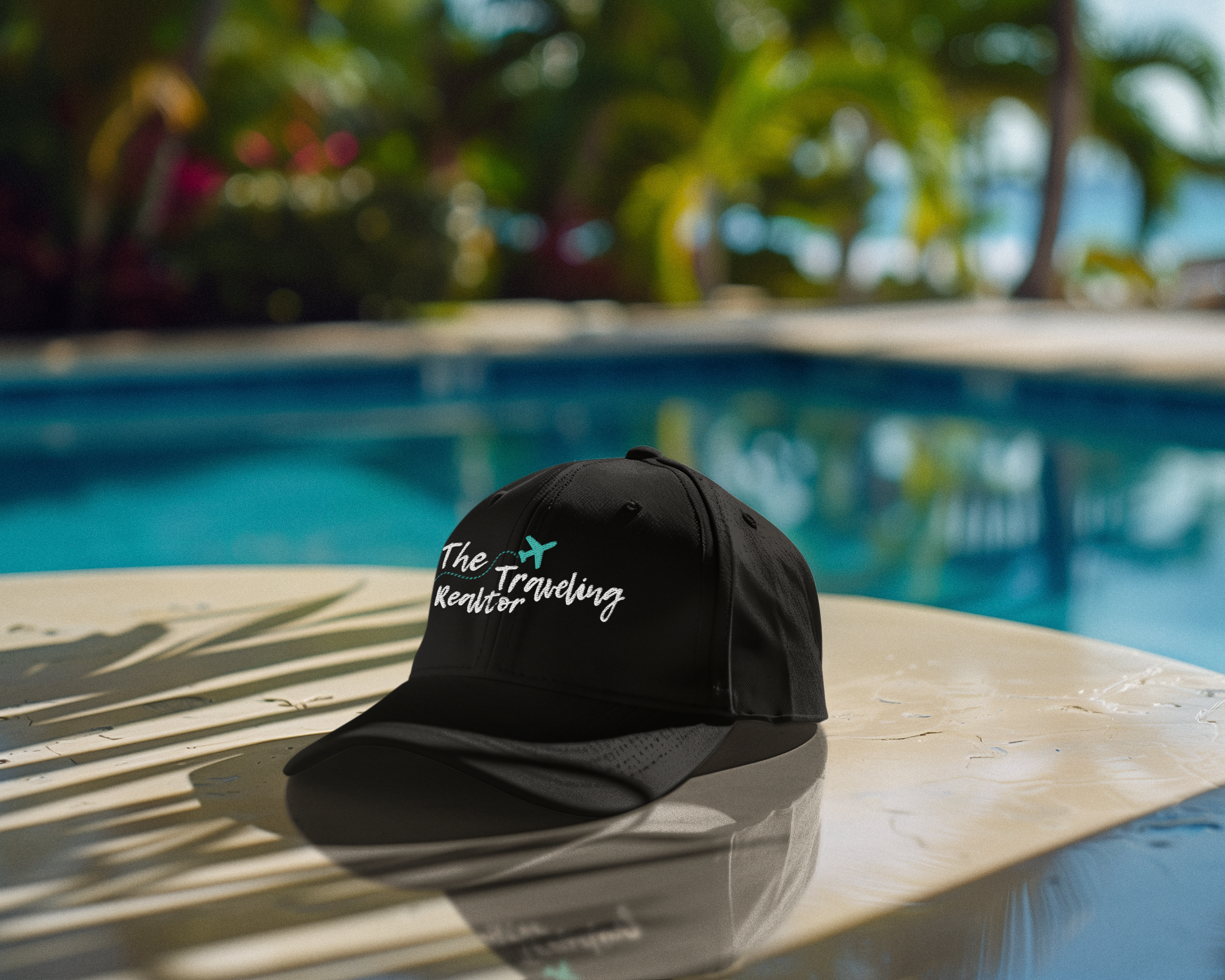 Black dad hat featuring The Traveling Realtor logo placed poolside showcasing branded accessory in a relaxed lifestyle setting