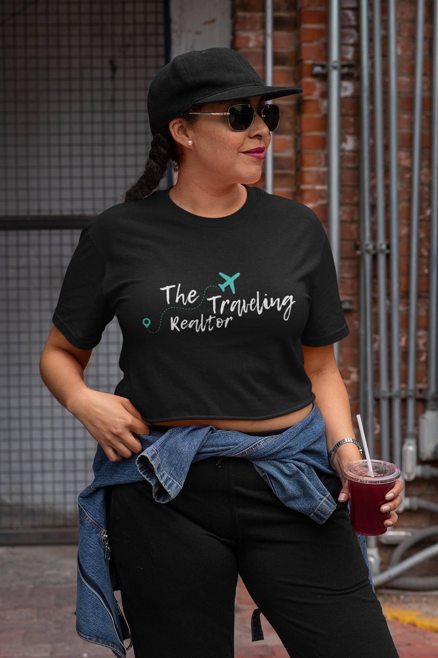Woman wearing a black cropped t-shirt with The Traveling Realtor logo styled in a casual streetwear look