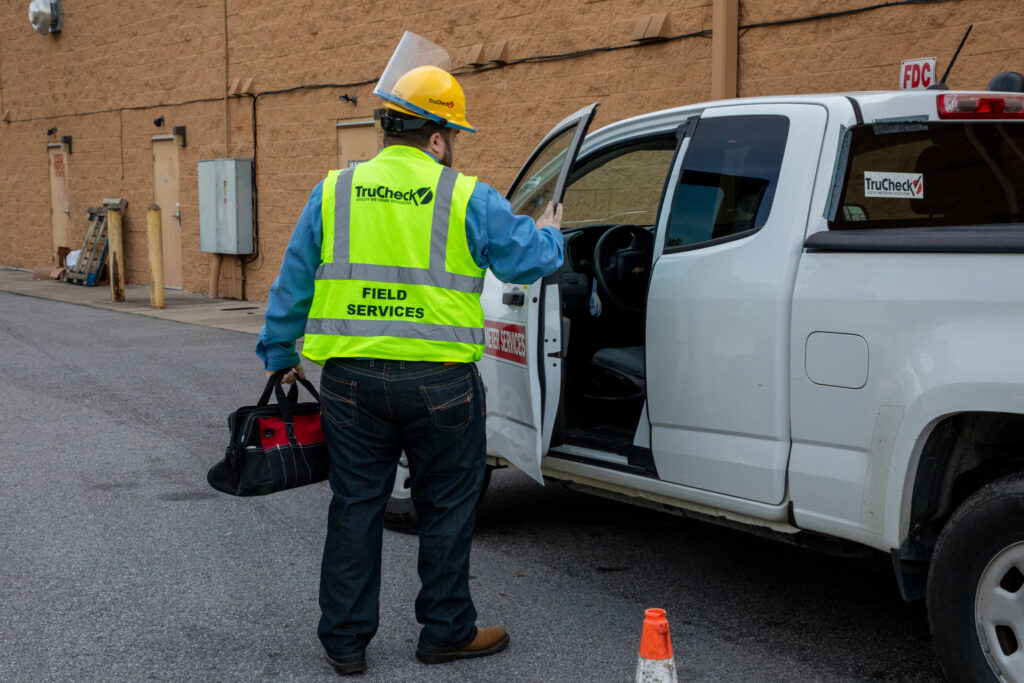 TruCheck field technician preparing for utility service work beside a branded company service vehicle.