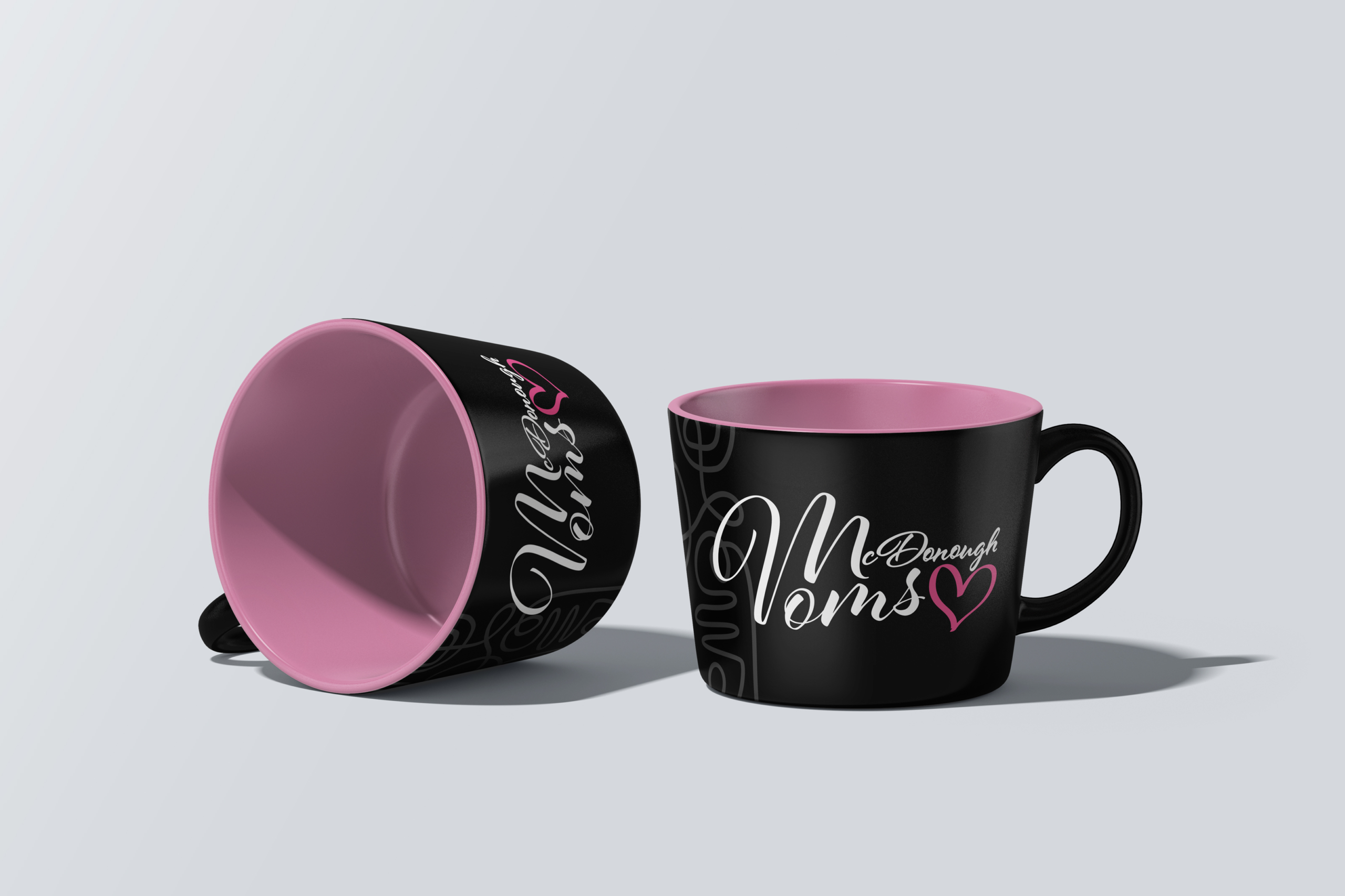 Black and pink McDonough Moms branded coffee mug mockup featuring the community logo application.