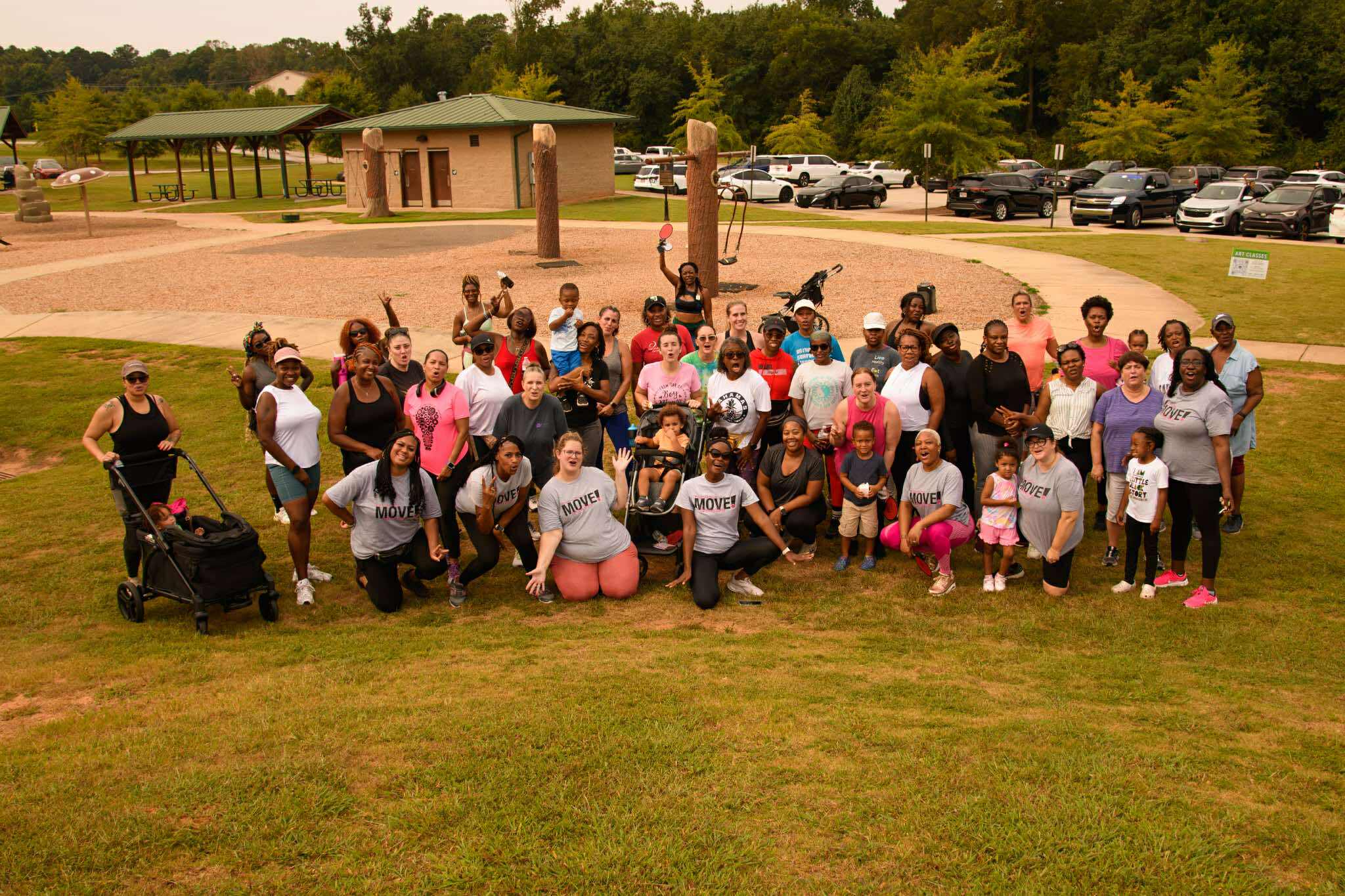Large group of women, children, and families gathered at a McDonough Moms MOVE community walking event at a local park.